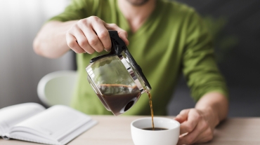 man-green-shirt-pouring-coffee-close-up